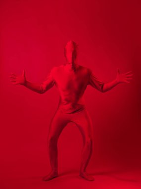 Kırmızı arka plandaki çılgın kızıl adam. Tüm vücudu saran bir tayt giymişti.