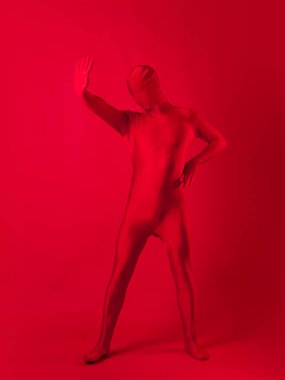 Kırmızı arka plandaki çılgın kızıl adam. Tüm vücudu saran bir tayt giymişti.