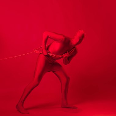 Kırmızı taytlı tedirgin kırmızı bir adam ağır bir yük taşıyor.,