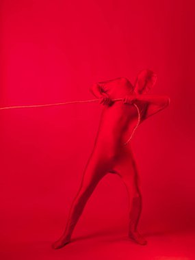 Kırmızı taytlı tedirgin kırmızı bir adam ağır bir yük taşıyor.,