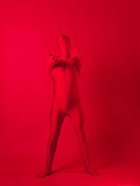 Kırmızı arka plandaki çılgın kızıl adam. Tüm vücudu saran bir tayt giymişti.