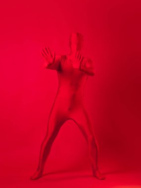 Kırmızı arka plandaki çılgın kızıl adam. Tüm vücudu saran bir tayt giymişti.