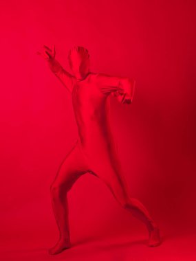 Kırmızı arka plandaki çılgın kızıl adam. Tüm vücudu saran bir tayt giymişti.