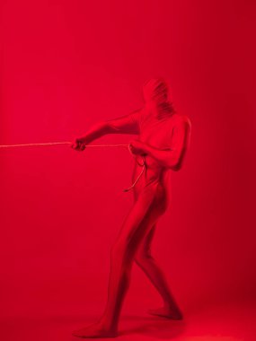 Kırmızı taytlı tedirgin kırmızı bir adam ağır bir yük taşıyor.,