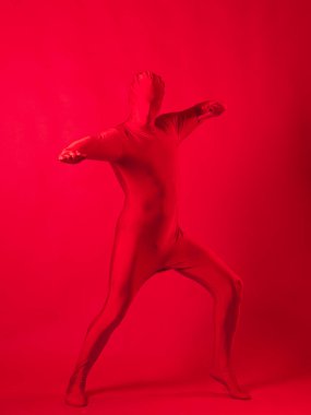 Kırmızı arka plandaki çılgın kızıl adam. Tüm vücudu saran bir tayt giymişti.