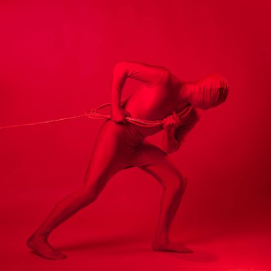 Kırmızı taytlı tedirgin kırmızı bir adam ağır bir yük taşıyor.,