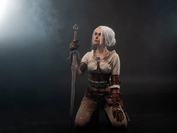 A young warrior with a sword on a dark background. Fantasy heroine — Stock Photo, Image