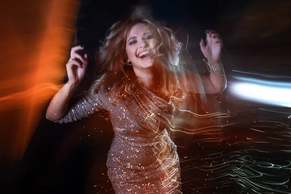 Schöne junge Frau in einem glänzenden Kleid tanzt in einem Nachtclub, — Stockfoto