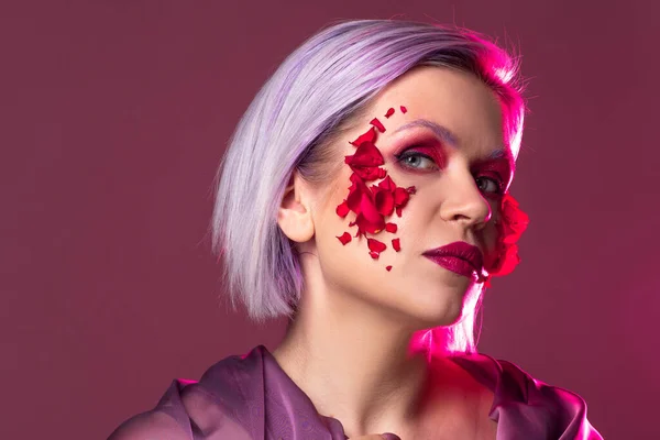 Mujer joven elegante y brillante con maquillaje de colores y pétalos de flores en su cara —  Fotos de Stock