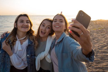 Kumsalda yürüyen üç arkadaş, iletişimin mutluluğu..