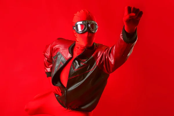 A funny super hero in a red leotard and protective glasses flying forward. — Stock Photo, Image