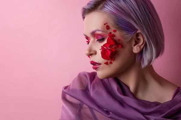 Stilren och ljus ung kvinna med färgad makeup och blomblad i ansiktet — Stockfoto