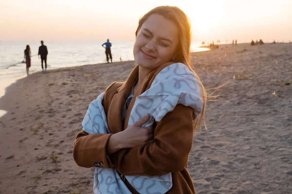 Jeune belle femme enveloppée dans une couverture chaude, chaleureuse et confortable sur la plage. — Photo
