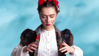 Saçında kırmızı güller olan Meksikalı sanatçı Frida 'ya benzeyen genç bir kadın..