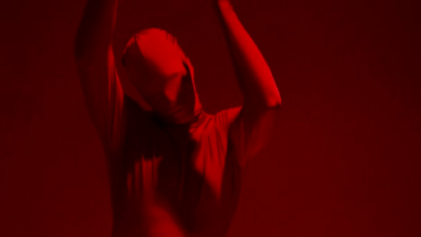 Ein tanzender Wahnsinniger in einem roten Ganzanzug auf rotem Hintergrund. — Stockvideo