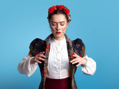 Saçında kırmızı güller olan Meksikalı sanatçı Frida 'ya benzeyen genç bir kadın..