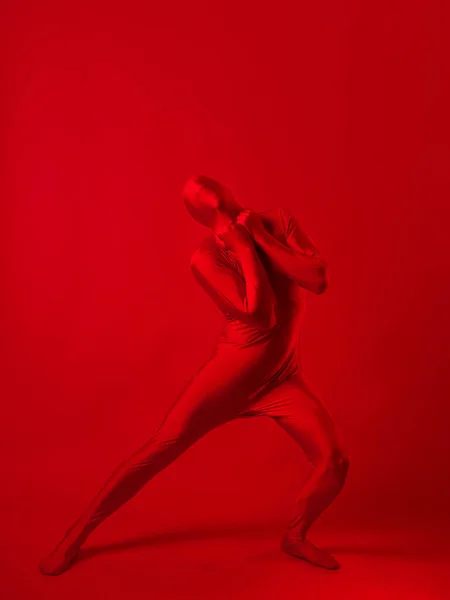 Galen röd man på en röd bakgrund. figur i en trikå som täcker hela kroppen — Stockfoto