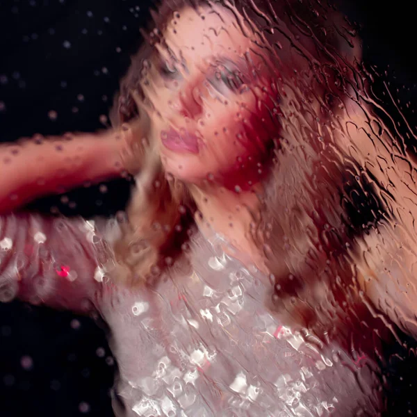 Mystiskt porträtt av en vacker ung blondin med droppar på glaset — Stockfoto