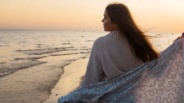 Jeune belle femme enveloppée dans une couverture chaude, chaleureuse et confortable sur la plage. — Photo