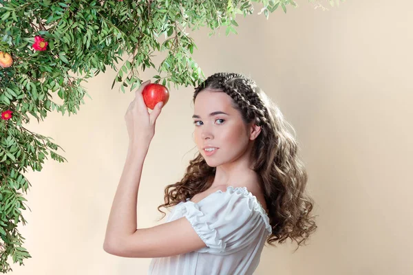 Jovem bela mulher no jardim do Éden arranca uma fruta madura. — Fotografia de Stock