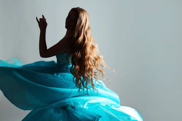 Misteriosa joven con el pelo ondulado largo y un vestido azul exuberante. — Foto de Stock