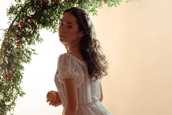 Jonge mooie vrouw in de tuin van Eden plukt een rijpe vrucht. — Stockfoto