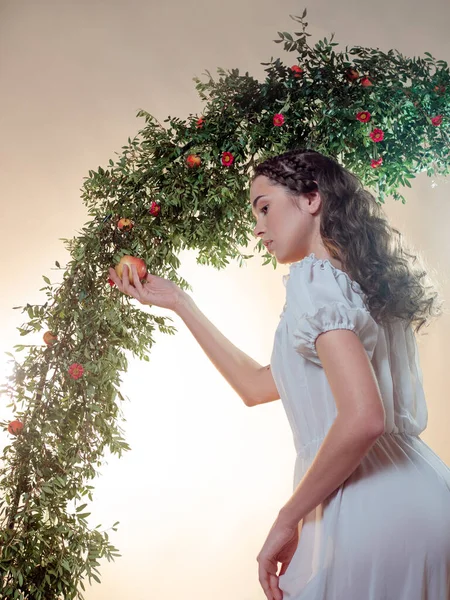 Jovem bela mulher no jardim do Éden arranca uma fruta madura. — Fotografia de Stock