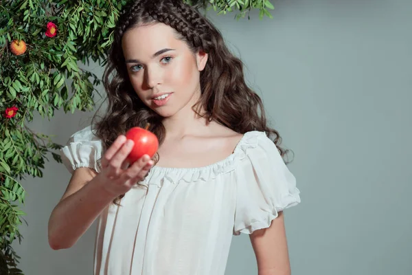 Una joven hermosa mujer en el jardín del Edén prueba una fruta madura. —  Fotos de Stock