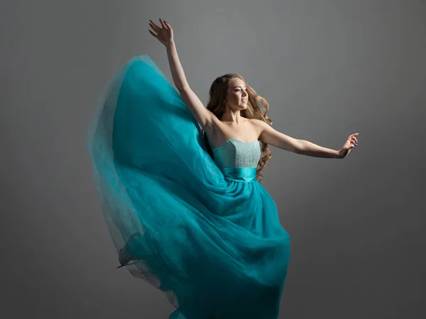 A beautiful and happy young woman with long wavy hair and a lush blue dress. — Stock Photo, Image