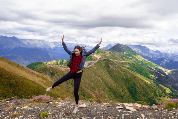 Alegre joven mujer después de un exitoso senderismo diversión salta en la cima de la montaña. — Foto de Stock