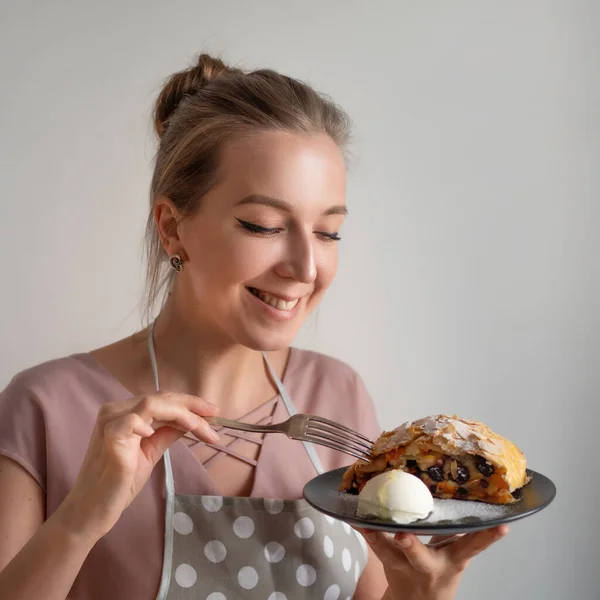 Cozinheiro chef feminino feliz no avental mantém um prato com strudel de maçã fresca — Fotografia de Stock