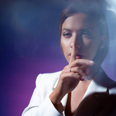 Genç bir kadın sessizlik jesti yapıyor. Modaya uygun genç bir kadın.