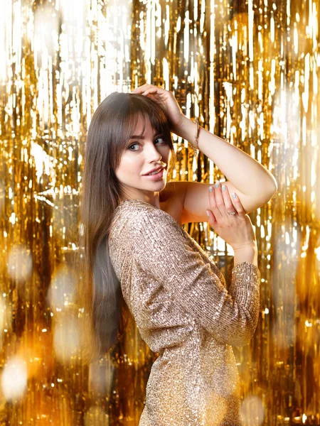 Birthday or New Years eve party. Young beautiful brunette in a gold dress — Stock Photo, Image