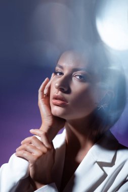 Beyaz dinamik bir portrede kristal yüzeylerle şık ve şık genç bir kadın.