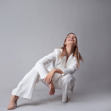 Beyaz takım elbiseli, ceketli ve pantolonlu güzel bir kadın.,