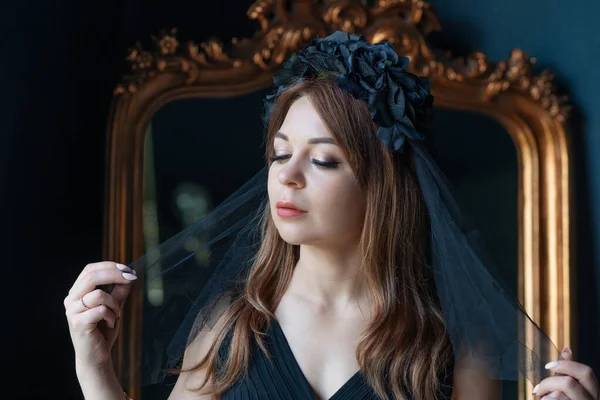 Una joven con un vestido negro y un velo negro en la cabeza — Foto de Stock