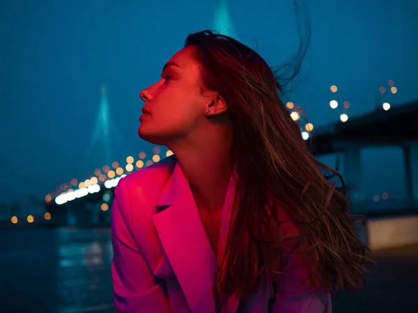 Una giovane bruna elegante nelle luci della città notturna, illuminazione al neon, — Foto Stock