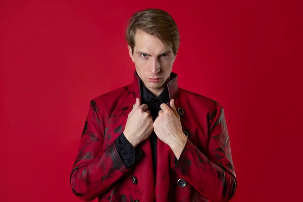 Un giovane oltraggioso con un cappotto rosso audace in stile vintage noir, — Foto Stock