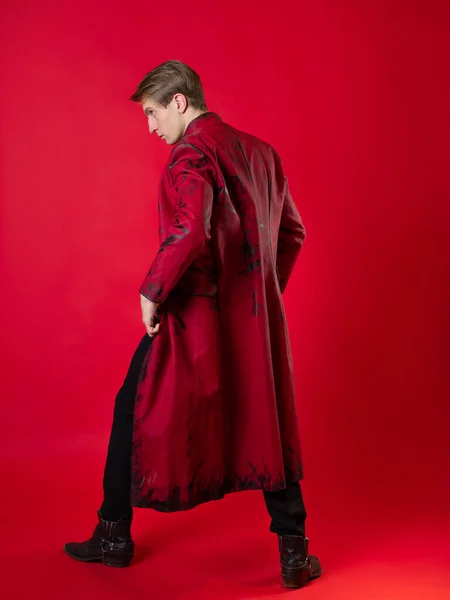 Un jeune homme scandaleux dans un manteau rouge audacieux dans un style noir vintage, — Photo