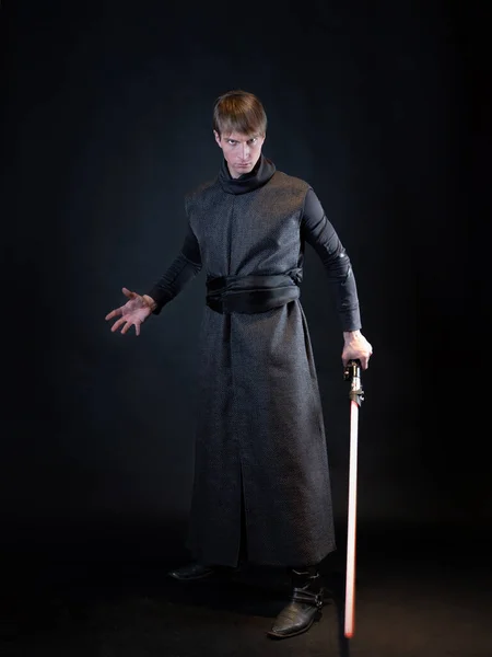 Ein Bösewicht mit rotem Lichtschwert, ein junger Mann in langer Robe in Kampfpose, — Stockfoto