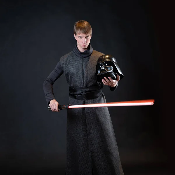 Un cattivo con una spada laser rossa, un giovane con una lunga veste combatte pose, — Foto Stock