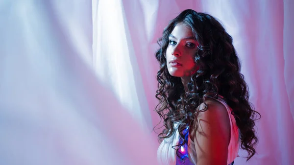 Hermosa joven morena con el pelo rizado, retrato en luz de neón, rojo brillante — Foto de Stock