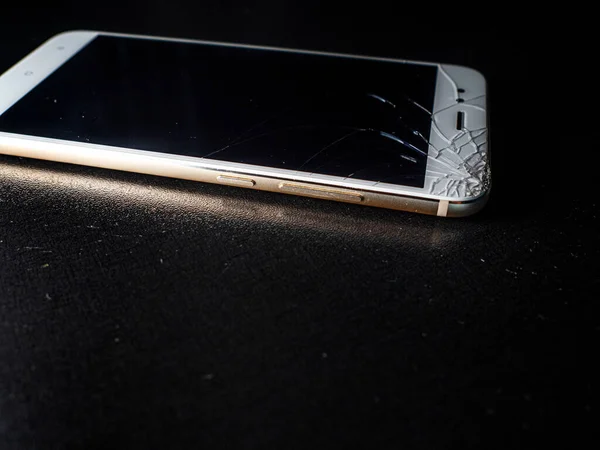 Een dunne witte smartphone met een slecht gebarsten scherm, beschadiging bij vallen. — Stockfoto