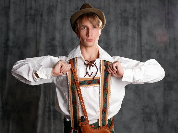 Een jongeman in een nationaal Beiers pak met shorts op bretels en een hoed.. — Stockfoto