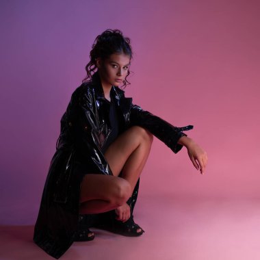 Siyah bir vücut giysisinin üzerine lateks yağmurluk giymiş şık bir esmer.,