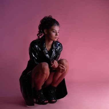 Siyah bir vücut giysisinin üzerine lateks yağmurluk giymiş şık bir esmer.,