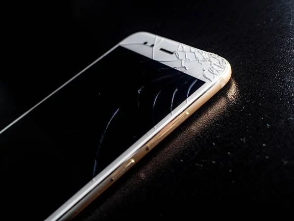 Een dunne witte smartphone met een slecht gebarsten scherm, beschadiging bij vallen. — Stockfoto