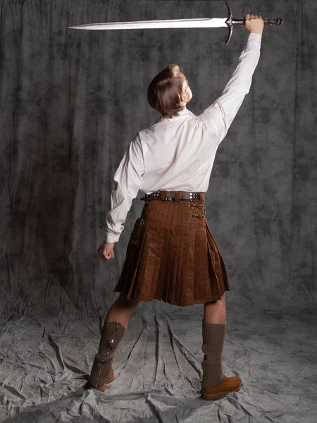 A young man in a leather kilt and a white lace-up blouse. A Scottish knight — Stock Photo, Image