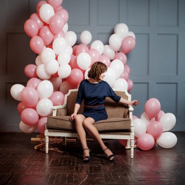 şişme balon dolu bir odada kanepede oturan genç kadın