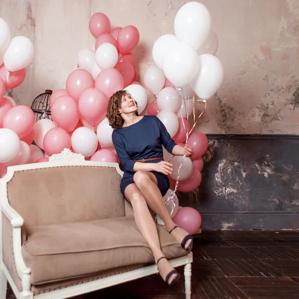 Jonge vrouw op de Bank in een kamer vol van Luchtballons Opblaasbare — Stockfoto